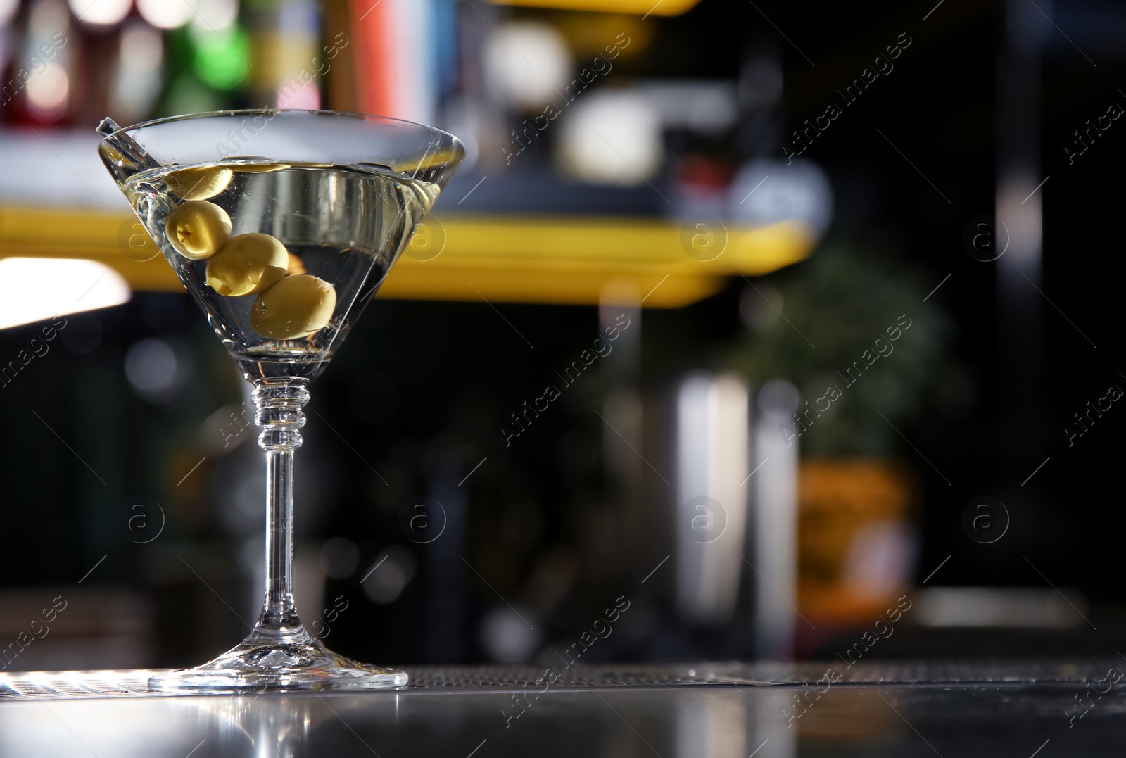 Photo of Glass of martini cocktail with olives on bar counter. Space for text