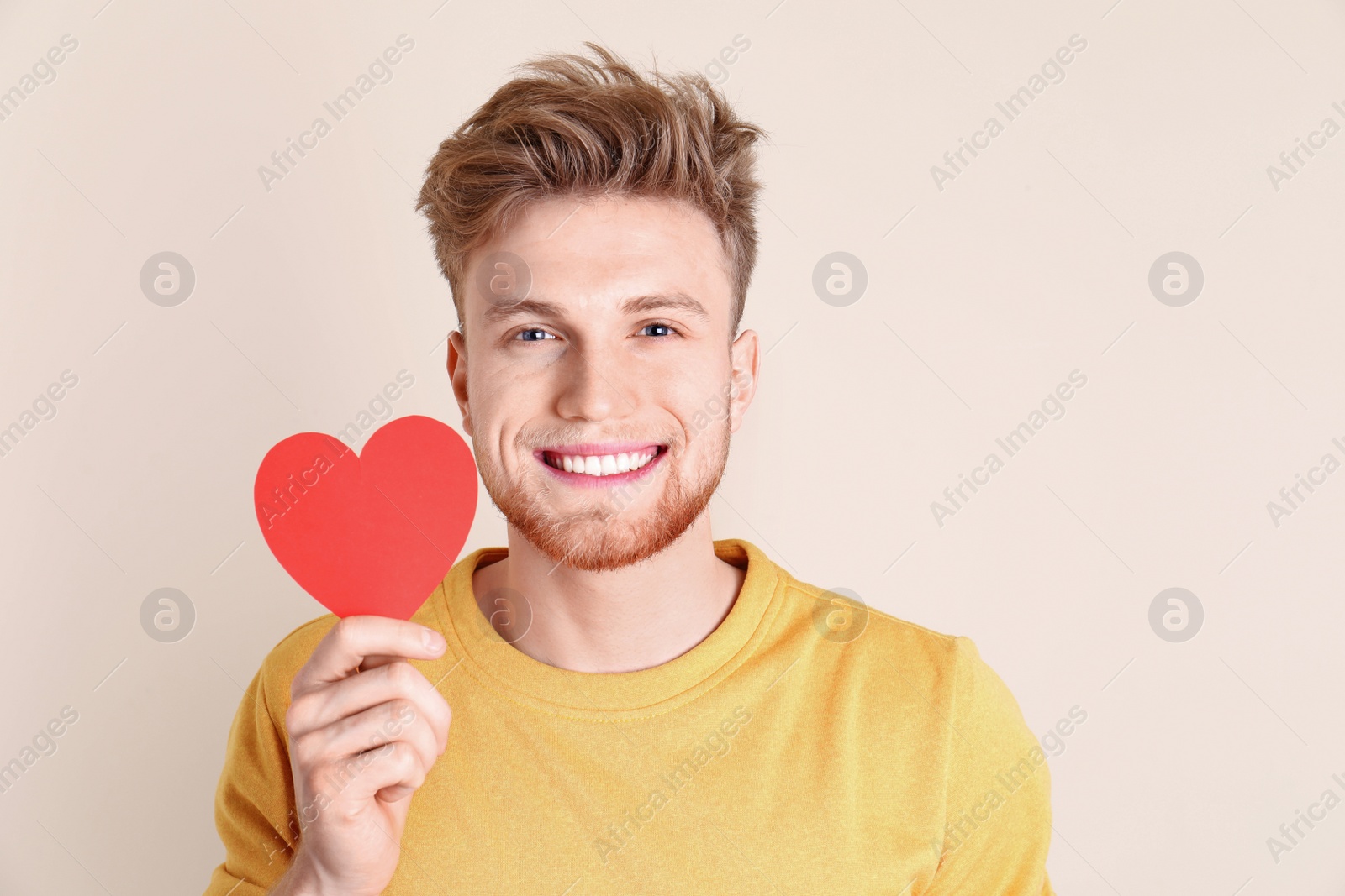 Photo of Portrait of young man with paper heart on color background