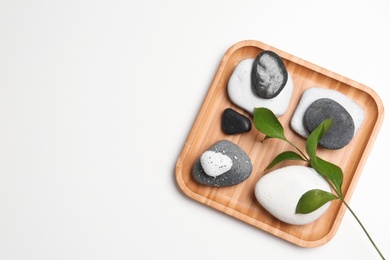 Plate with spa stones and space for text on white background, top view