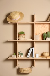 Wooden shelves with different decorative elements on beige wall