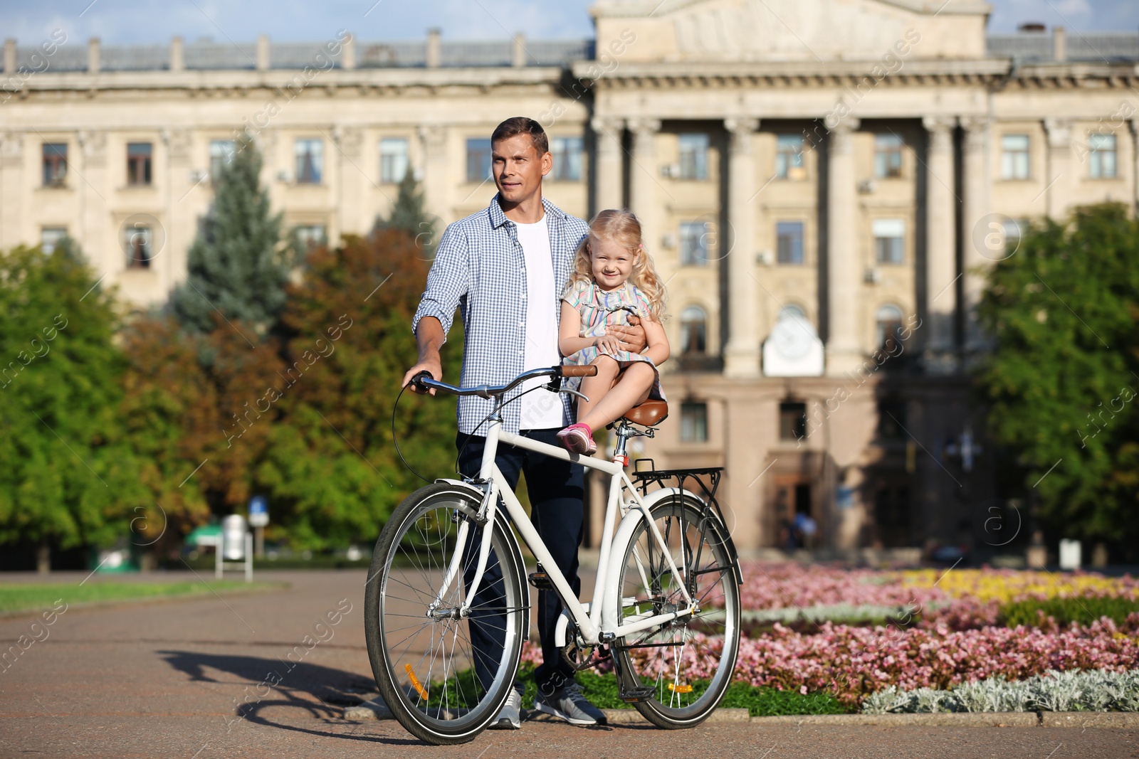 Photo of Happy father and his daughter with bicycle outdoors on sunny day