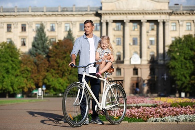 Happy father and his daughter with bicycle outdoors on sunny day