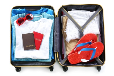 Packed suitcase with clothes and passports on white background, top view