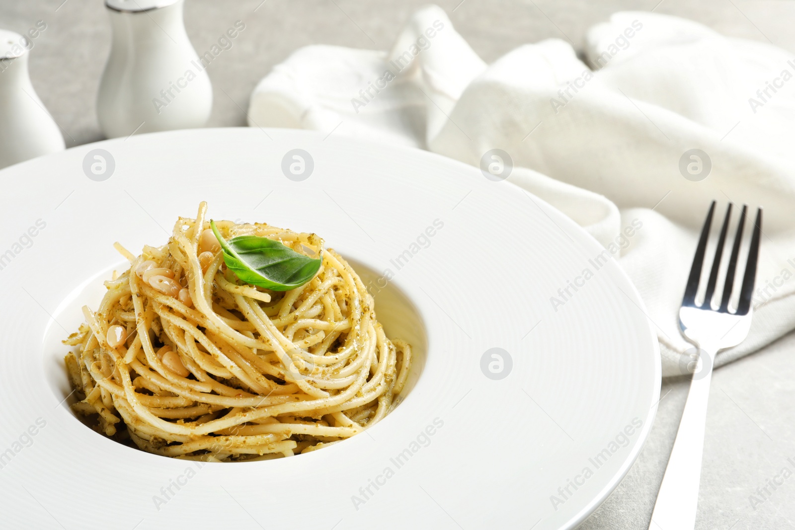 Photo of Plate of delicious basil pesto pasta served for dinner on table, closeup