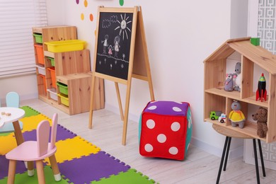 Photo of Stylish kindergarten interior with table, blackboard and toys