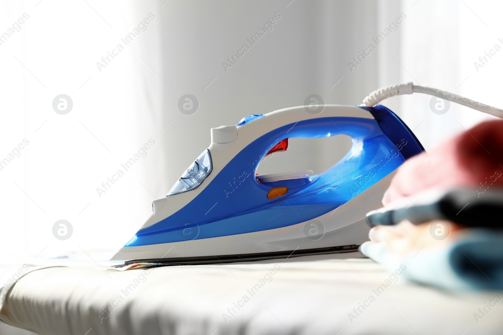 Photo of Modern electric iron on board indoors. Household appliance