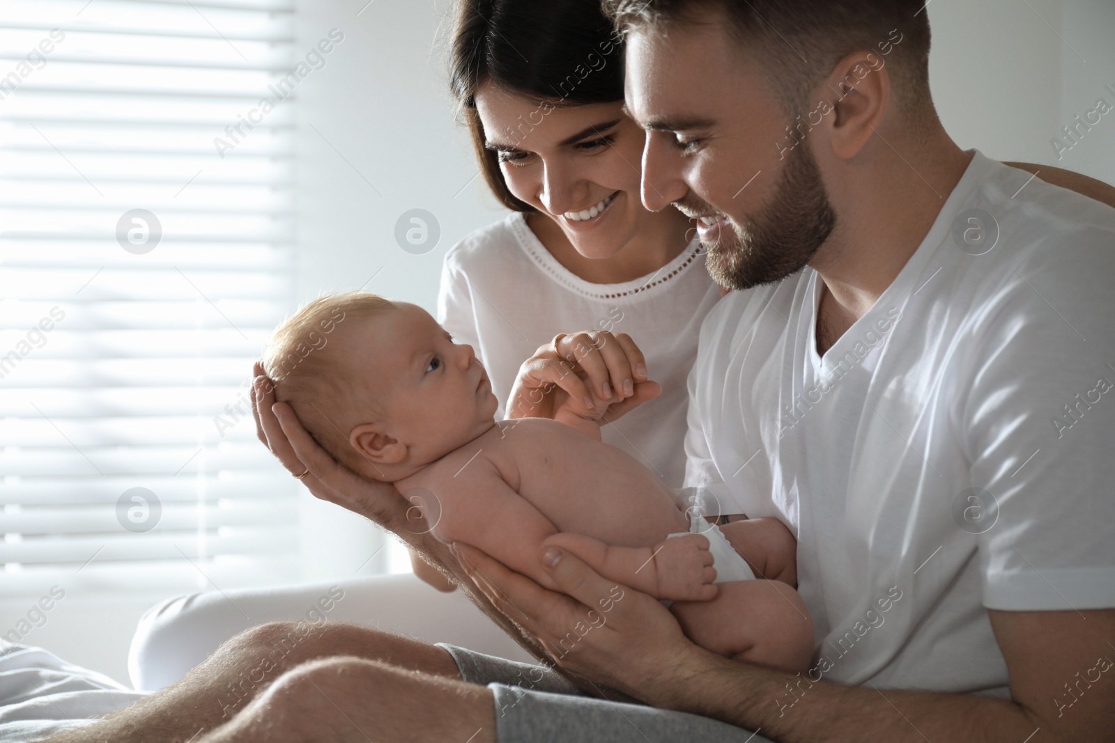 Photo of Happy couple with their newborn baby at home