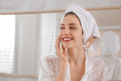 Photo of Beautiful young woman with hair wrapped in towel after washing at home