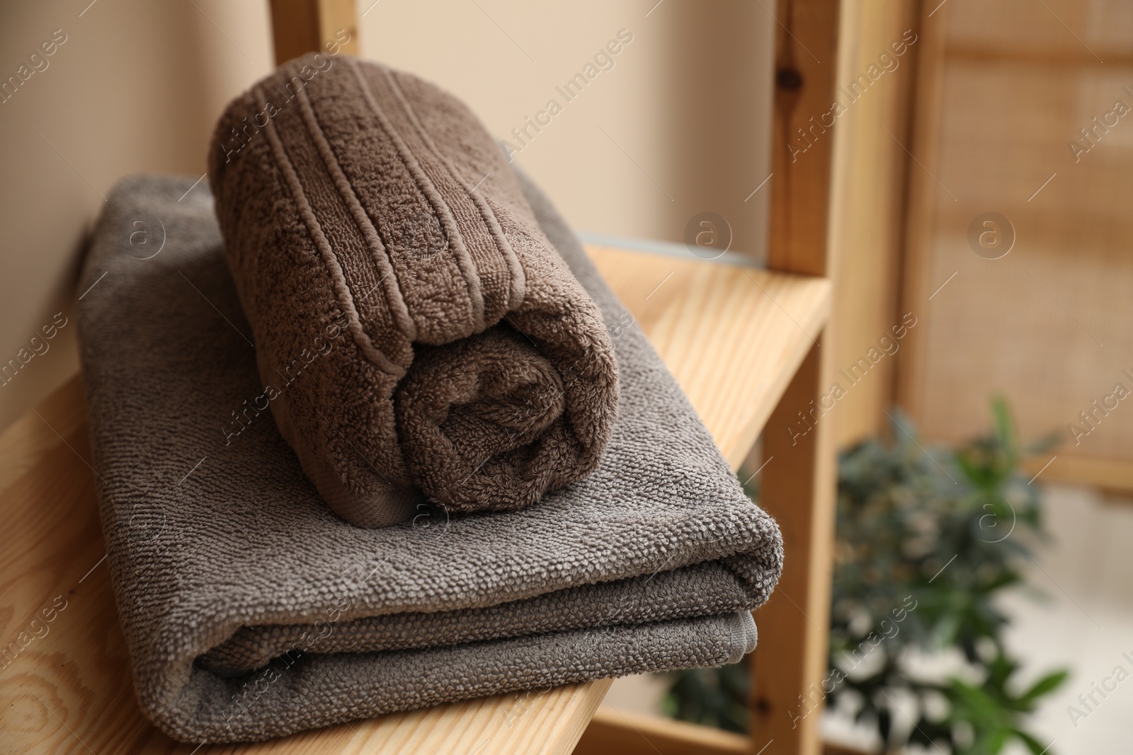 Photo of Soft towels on wooden shelf indoors, closeup