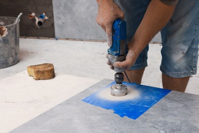Photo of Worker making socket hole in tile indoors, closeup