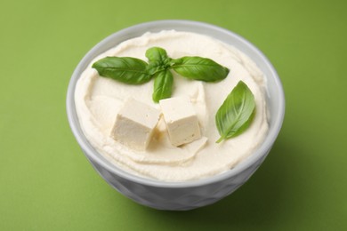 Photo of Delicious tofu sauce and basil leaves on green background, closeup