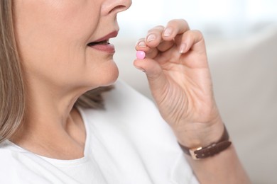 Photo of Senior woman taking pill indoors, closeup view
