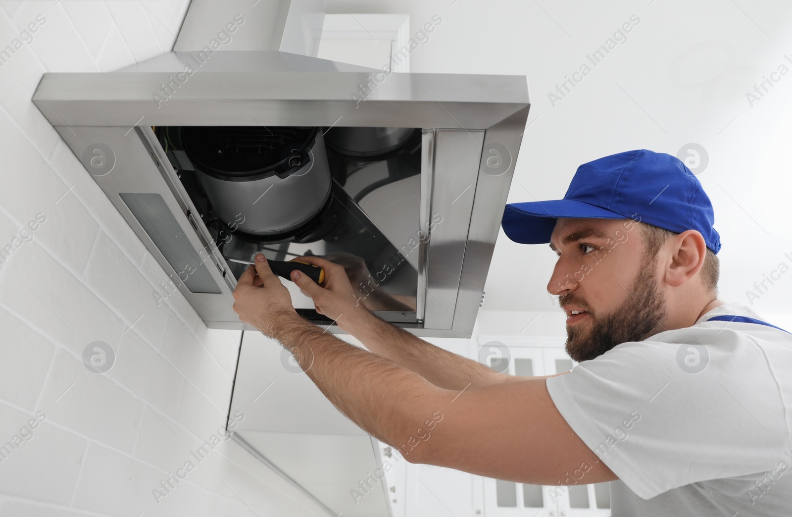 Photo of Worker repairing modern cooker hood in kitchen