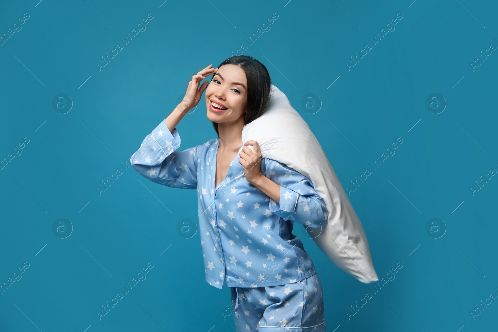 Photo of Beautiful Asian woman with pillow on blue background. Bedtime