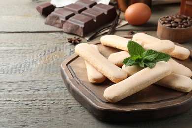Photo of Tasty cookies with mint and other tiramisu ingredients on wooden table, closeup. Space for text