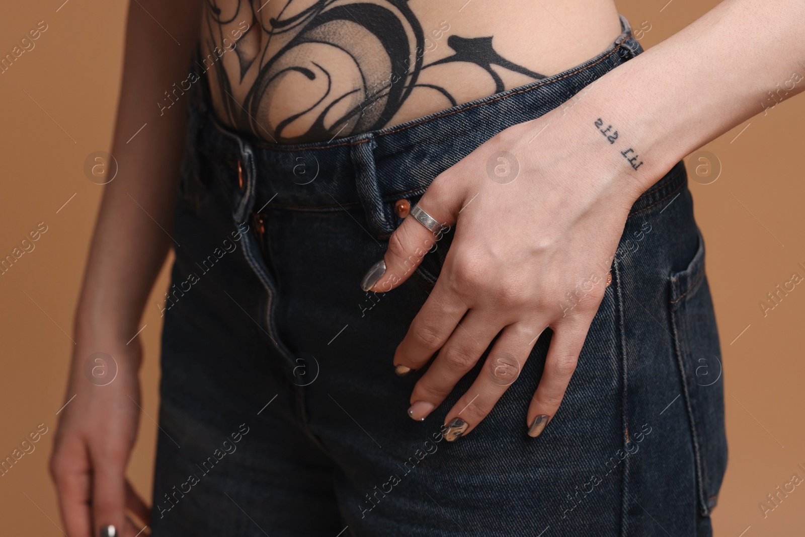 Photo of Woman with cool tattoos on beige background, closeup