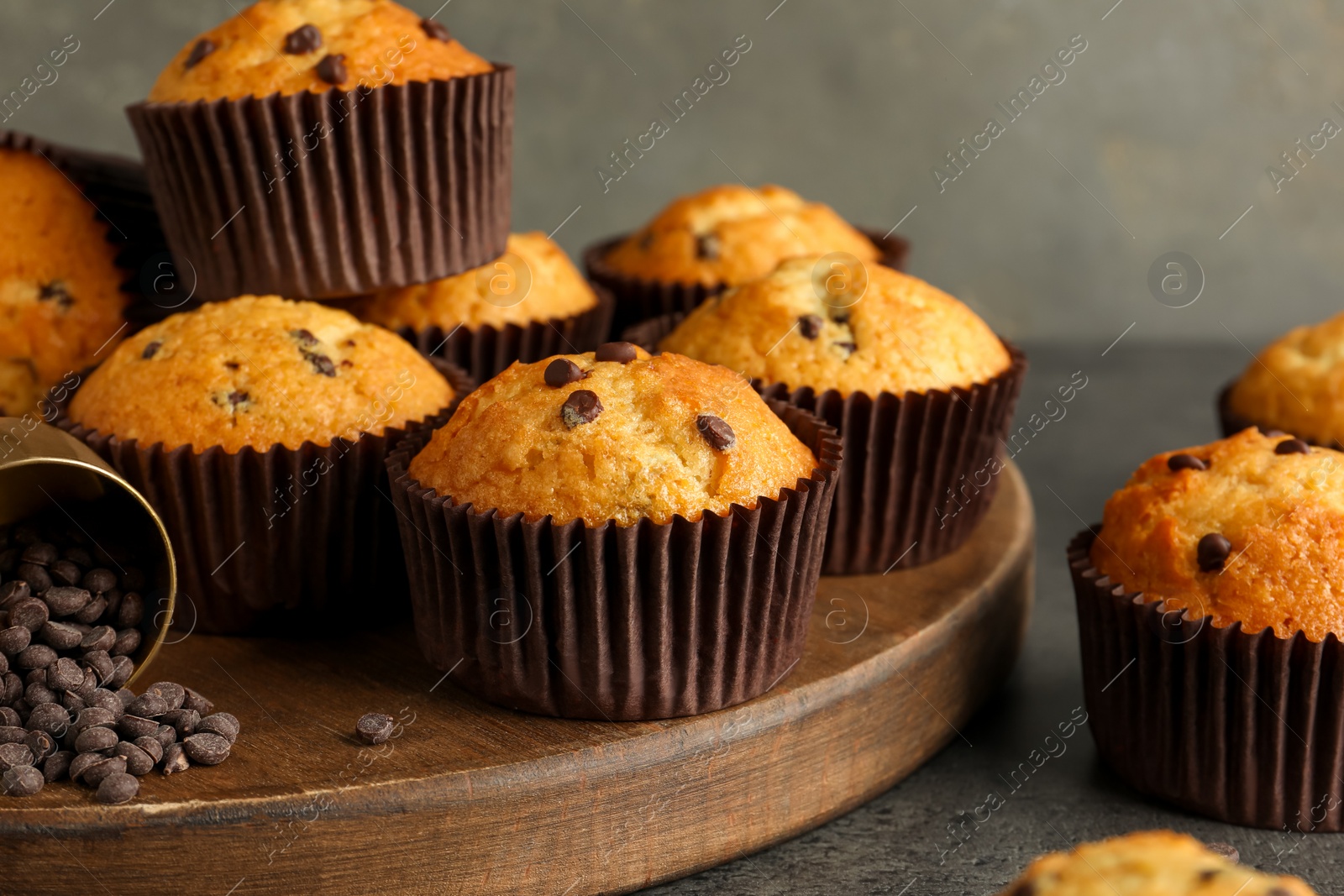 Photo of Delicious freshly baked muffins with chocolate chips on gray table, closeup