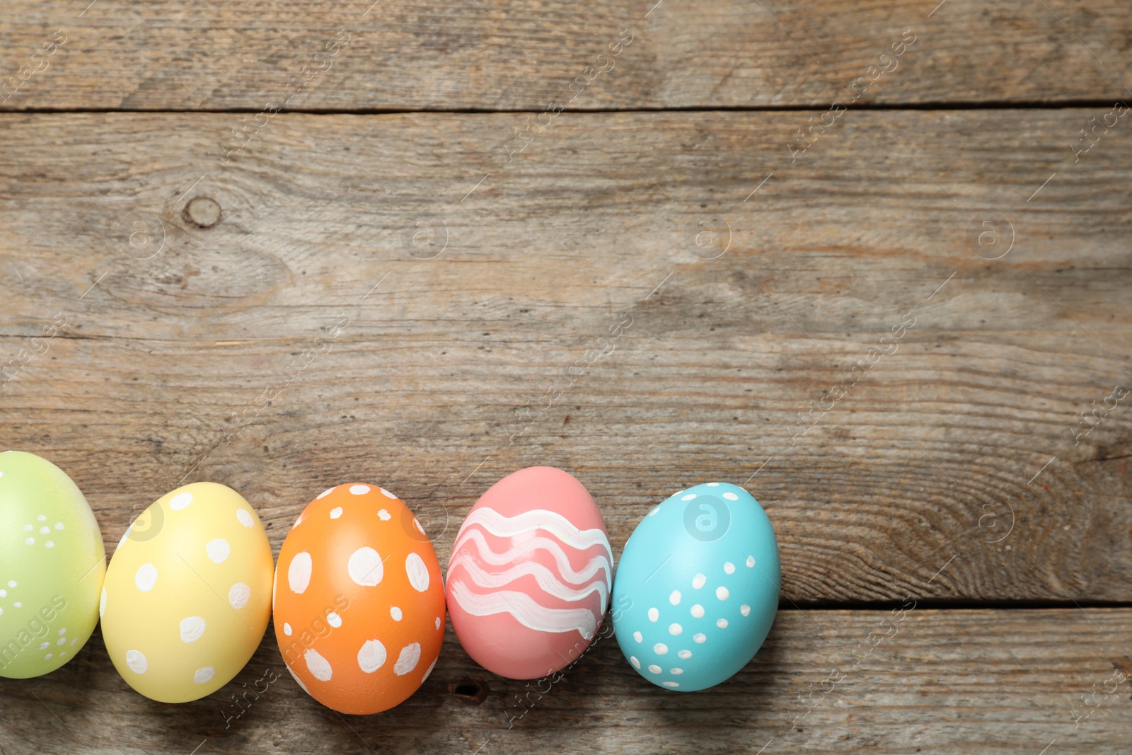 Photo of Flat lay composition of painted Easter eggs on wooden background, space for text