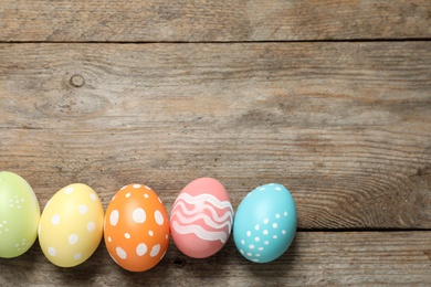 Photo of Flat lay composition of painted Easter eggs on wooden background, space for text