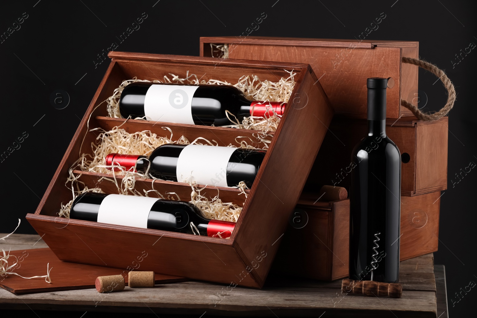 Photo of Box with wine bottles on wooden table against black background