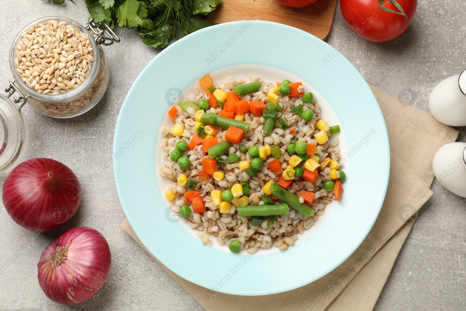 Photo of Tasty pearl barley porridge with vegetables on light textured table, flat lay