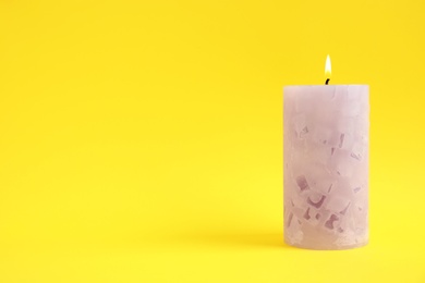 Photo of Alight wax candle on color background. Space for text