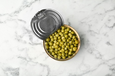 Photo of Tin can with conserved peas on marble background, top view