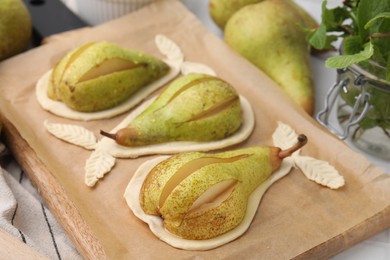 Board with raw dough, fresh pears and mint on white table, closeup