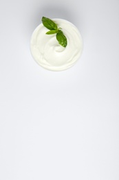 Photo of Bowl of fresh sour cream with basil on white background, top view