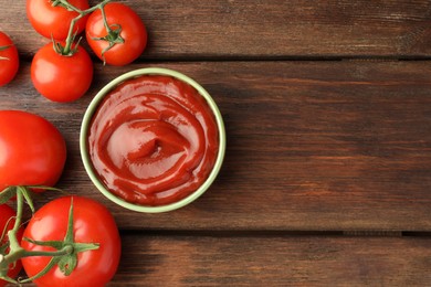 Bowl of tasty ketchup and tomatoes on wooden table, flat lay. Space for text