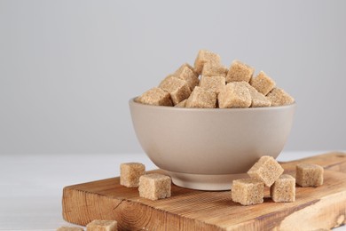 Photo of Brown sugar cubes on white table, space for text