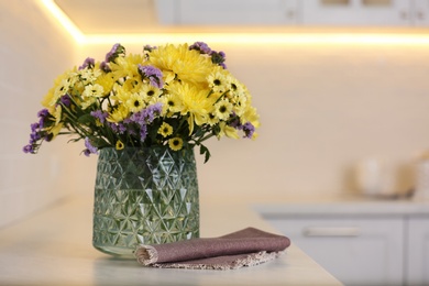 Vase with beautiful chrysanthemum flowers on countertop in kitchen, space for text. Interior design