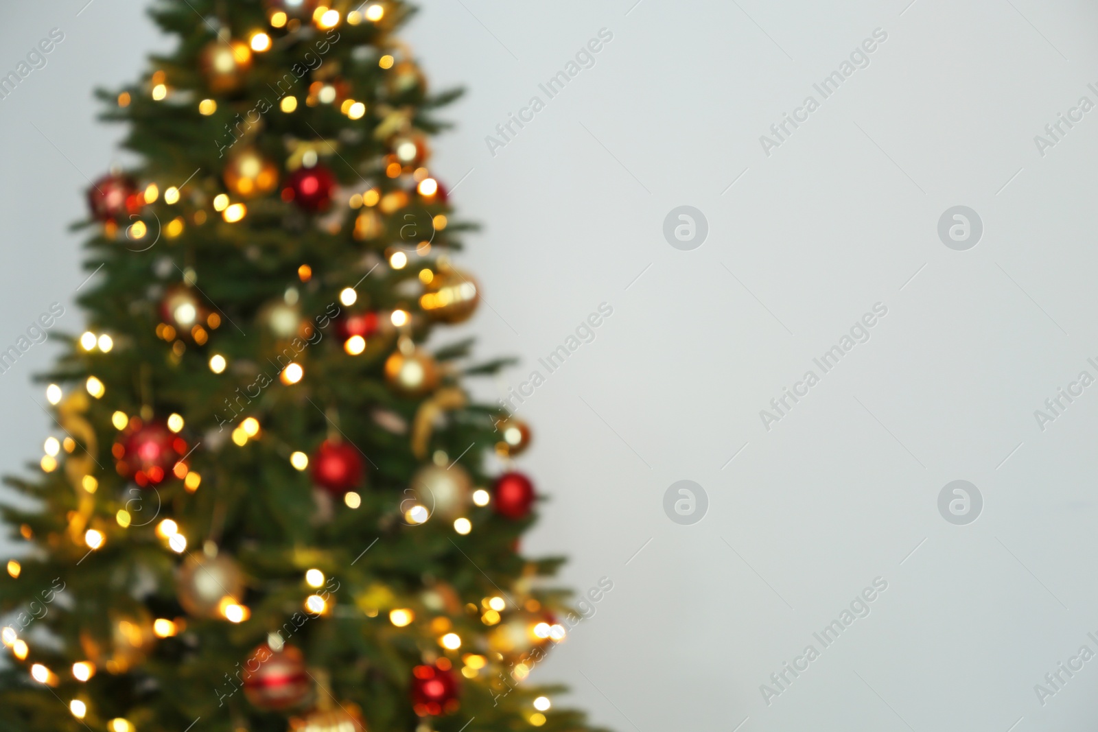 Photo of Blurred view of Christmas tree with fairy lights on white background