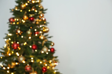 Blurred view of Christmas tree with fairy lights on white background