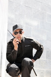 Photo of Male security guard using portable radio transmitter outdoors