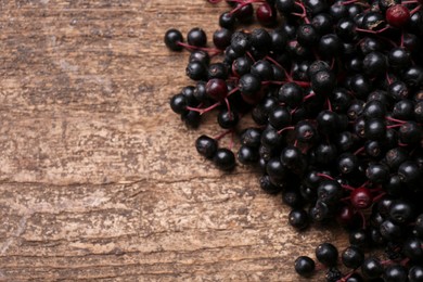 Pile of tasty elderberries (Sambucus) on wooden table, closeup. Space for text