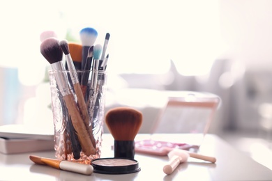 Holder with makeup brushes on table