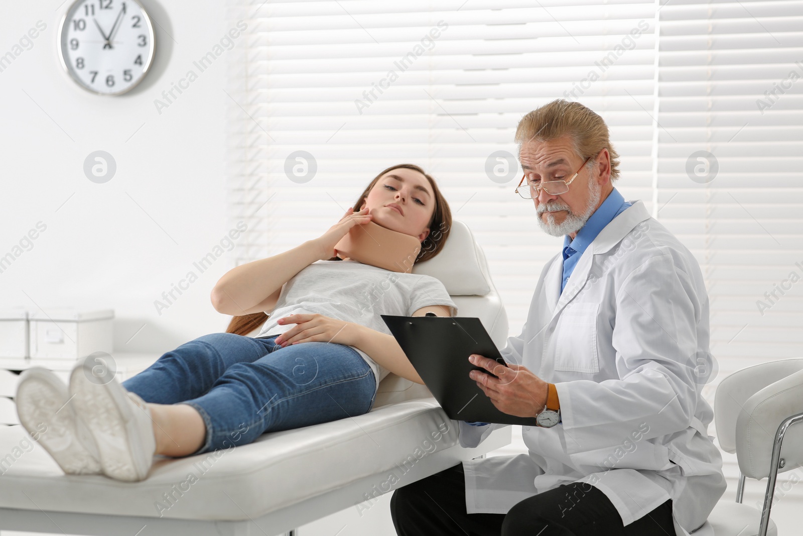 Photo of Orthopedist examining patient with injured neck in clinic