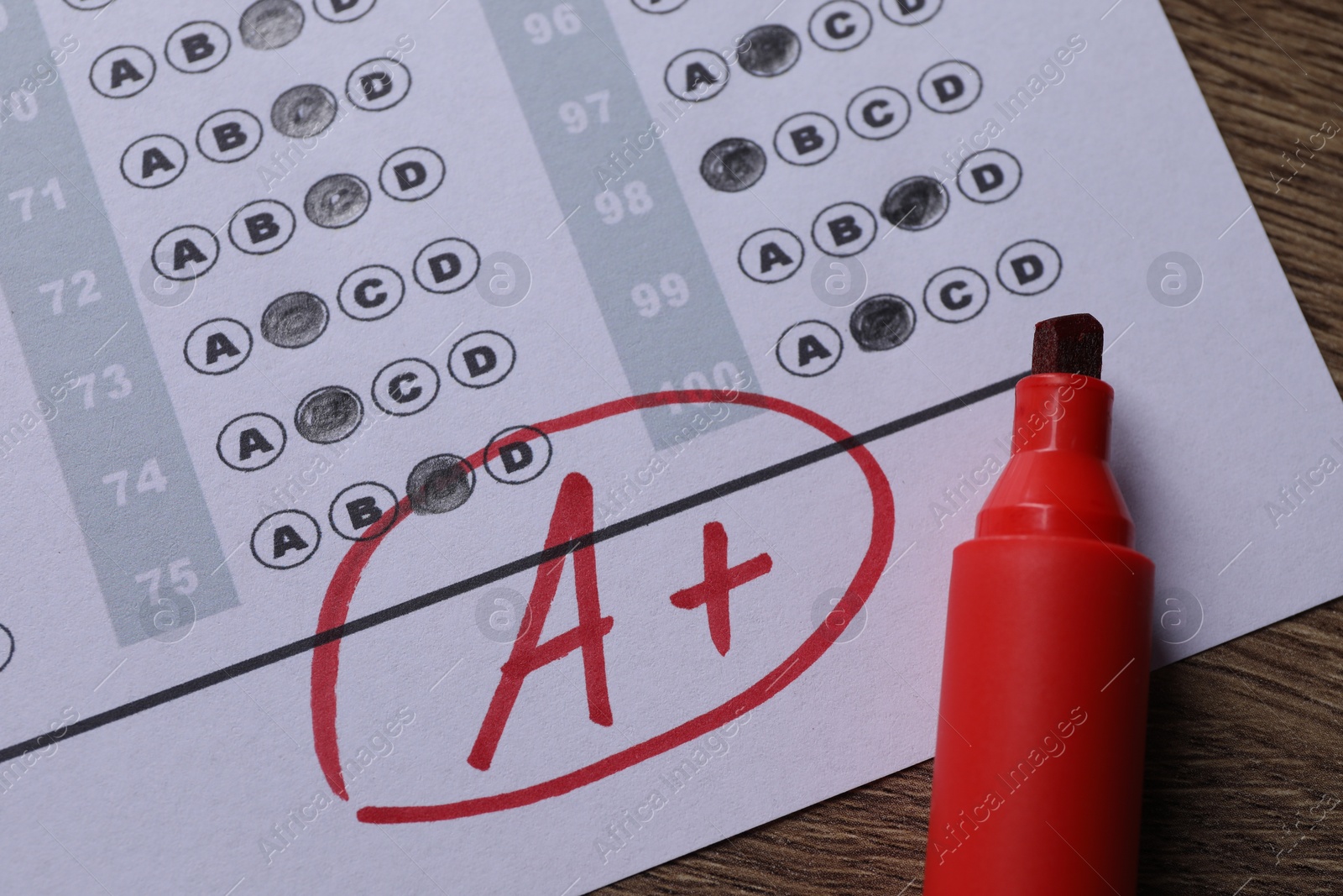 Photo of School grade. Answer sheet with red letter A, plus symbol and marker on wooden table, closeup