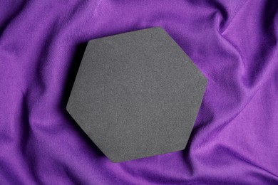 Photo of Black hexagon on purple fabric, top view. Stylish presentation for product