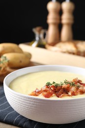 Photo of Tasty potato soup with bacon and rosemary in bowl on table, closeup