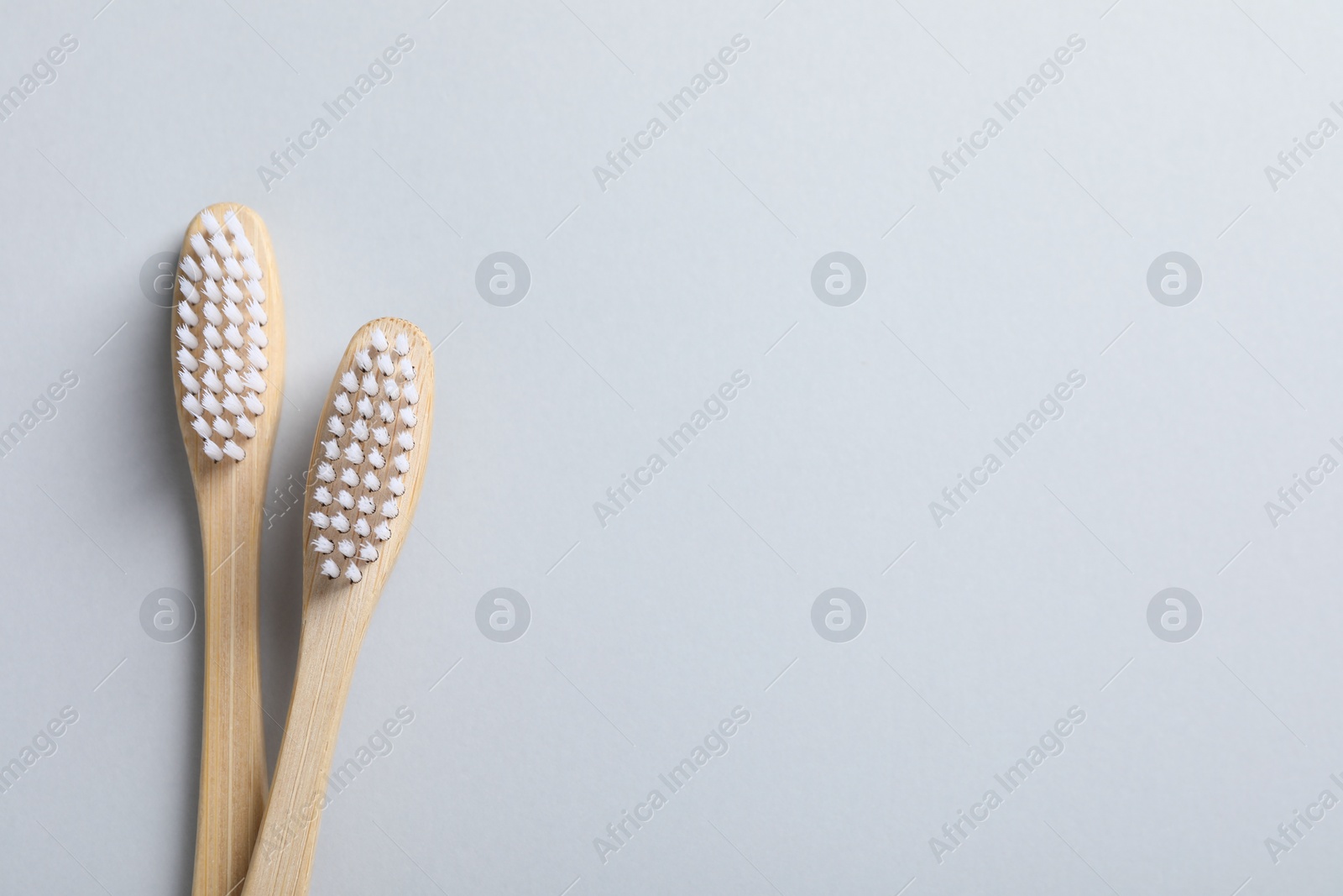 Photo of Bamboo toothbrushes on white background, flat lay. Space for text