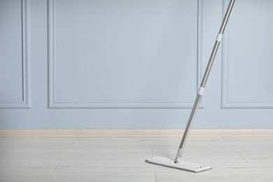 Photo of Cleaning of parquet floor with mop indoors, space for text