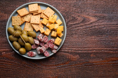 Photo of Toothpick appetizers. Pieces of cheese, sausage and olives on wooden table, top view with space for text