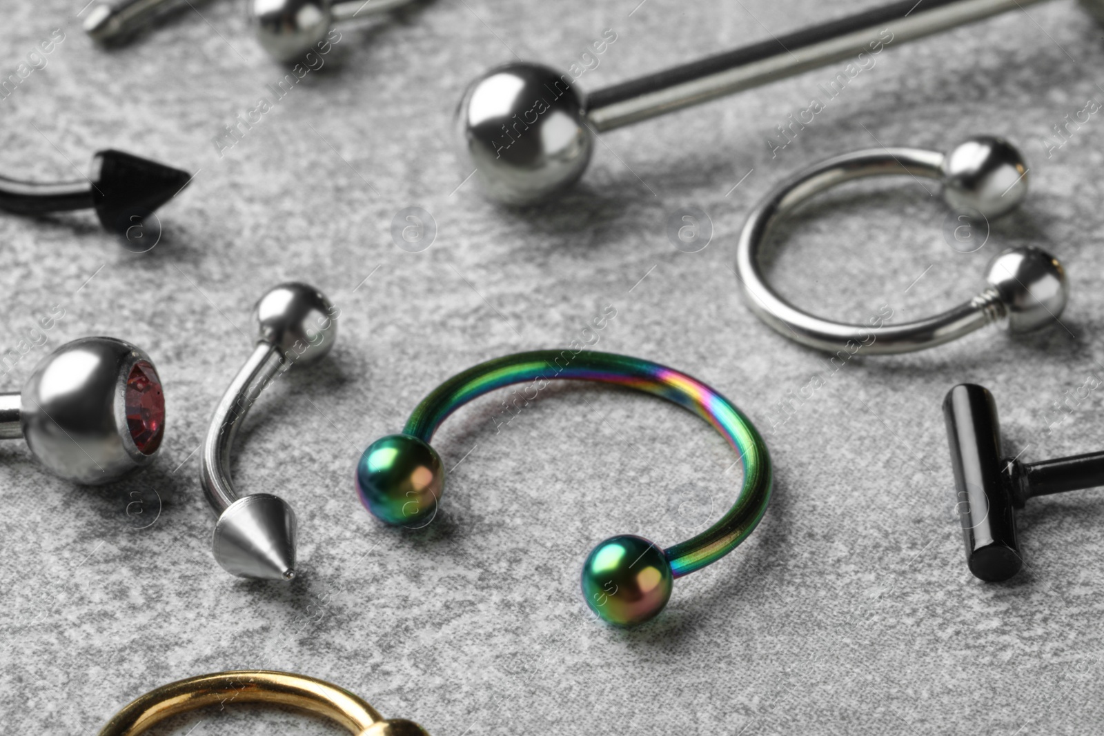 Photo of Stylish piercing jewelry on light grey table, closeup