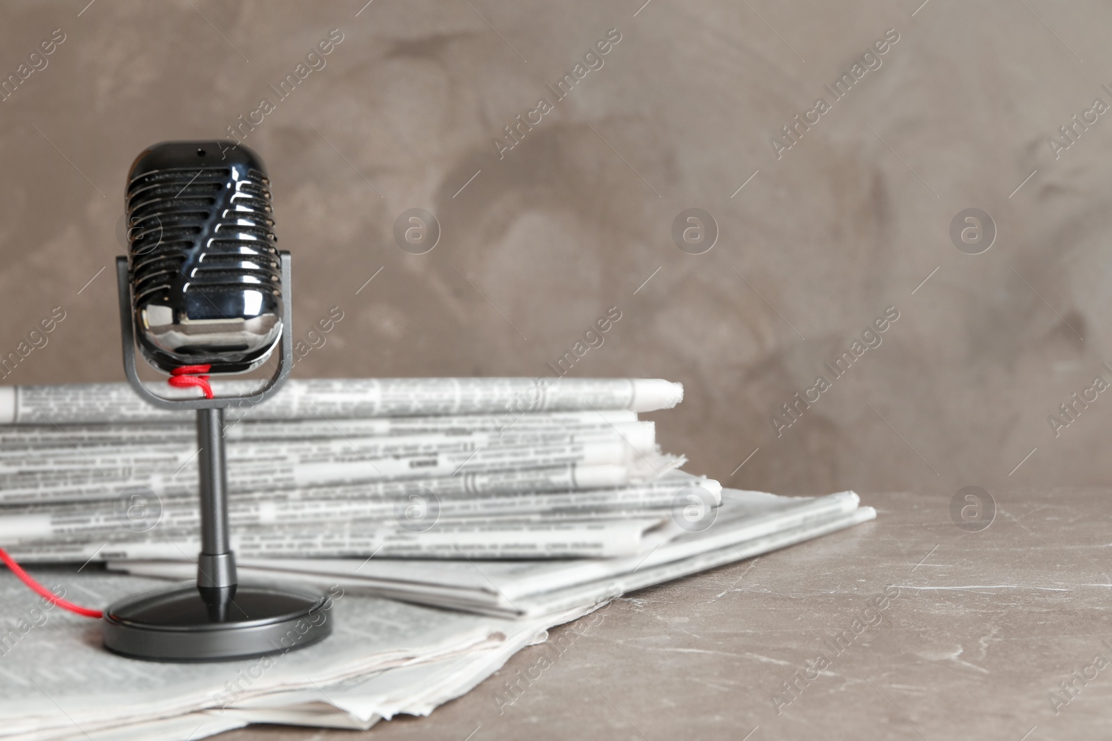 Photo of Newspapers and vintage microphone on marble table. Journalist's work