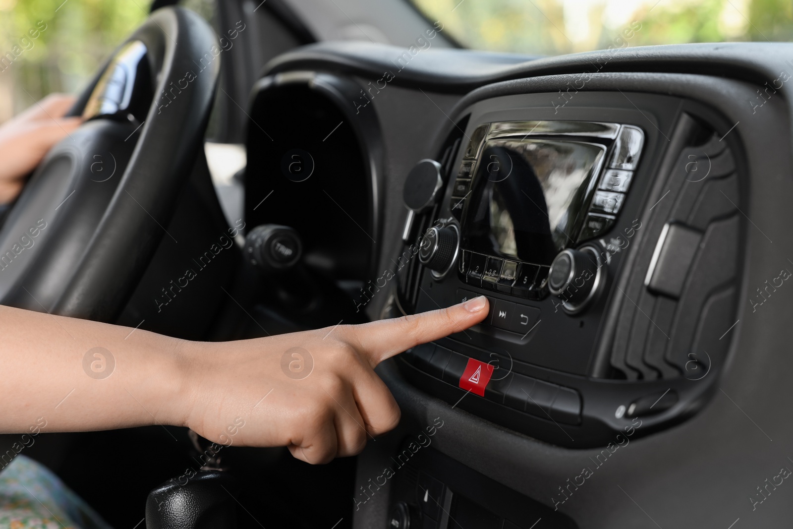 Photo of Choosing favorite radio. Woman pressing button on vehicle audio in car, closeup