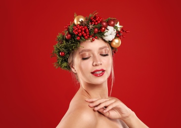 Photo of Beautiful young woman wearing Christmas wreath on red background