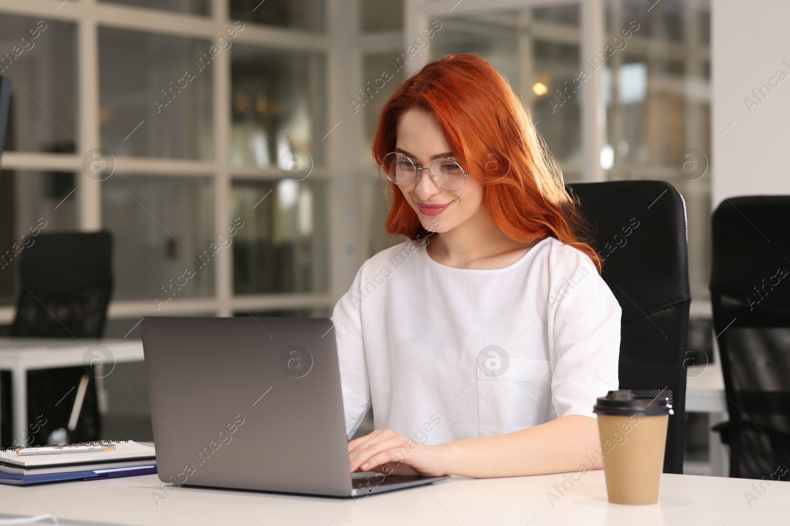 Photo of Happy woman working with laptop at white desk in office