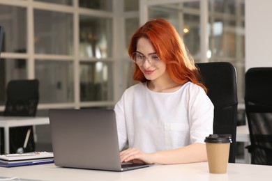Happy woman working with laptop at white desk in office